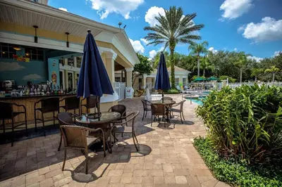 a patio with tables and umbrellas next to a pool at Silver Palms in Kissimmee