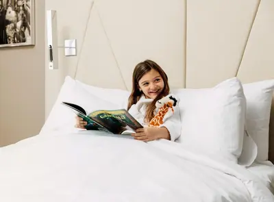 a little girl laying in bed reading a book at ette luxury hotel & spa - Near Disney Theme Parks in Orlando