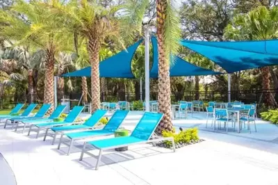 a row of blue lounge chairs and blue umbrellas at Spectacular big house, 4 Bedrooms, private pool in Kissimmee