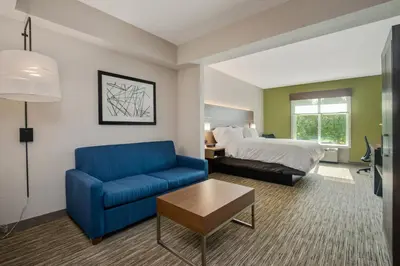 a hotel room with a bed and a blue couch at Holiday Inn Express Hotel & Suites Orlando - Apopka by IHG in Orlando