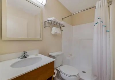 a bathroom with a sink and a toilet and a mirror at HomeTowne Studios by Red Roof Orlando - UCF Area in Orlando