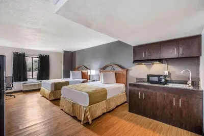 a hotel room with two beds and a kitchen at OYO Hotel Orlando Airport in Orlando