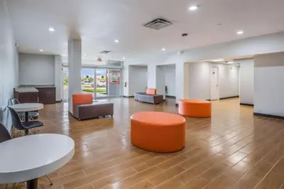 an office with orange chairs and tables and chairs at OYO Hotel Orlando Airport in Orlando