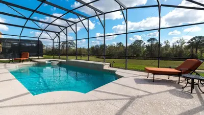 a swimming pool with two chairs and a glass house at Mickeys Maingate Mansion in Kissimmee