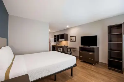 a bedroom with a bed and a desk with a television at WoodSpring Suites Orlando North - Maitland in Orlando