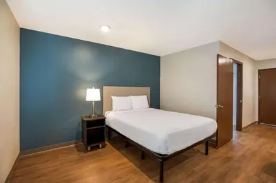 a bedroom with a bed and a blue wall at WoodSpring Suites Orlando North - Maitland in Orlando