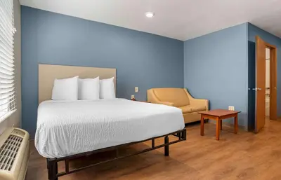 a bedroom with a large bed and a chair at Extended Stay America Select Suites - Orlando - Sanford - Airport in Sanford