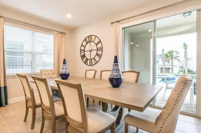 a dining room with a table and chairs and a clock at Welcoming Home With Air Hockey Table And Waterpark & Resort Access Near Disney At Encore Resorts Reunion - 321Bu in Kissimmee