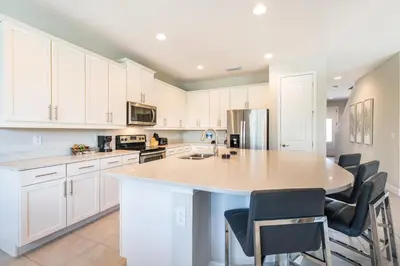 a kitchen with white cabinets and a large island at Cozy Home With Private Pool, Air Hockey Table And Themed Room Near Disney With Waterpark & Resort Access At Encore Resort - 7458Mr in Kissimmee