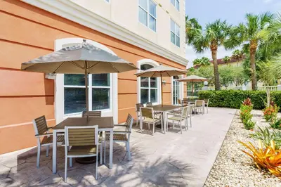 a patio with tables and chairs and an umbrella at Country Inn & Suites by Radisson, Orlando Airport, FL in Orlando
