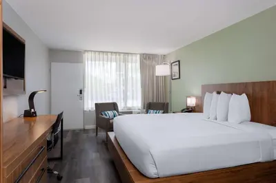a hotel room with a large white bed and a desk at Ramada by Wyndham Altamonte Springs Near I-4 in Orlando