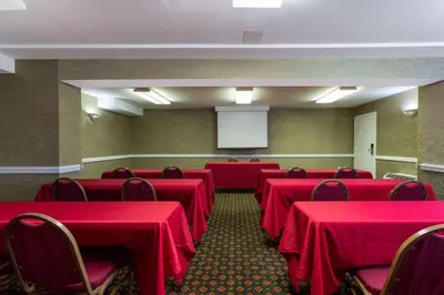 a conference room with red tables and chairs and a screen at Ramada by Wyndham Altamonte Springs Near I-4 in Orlando