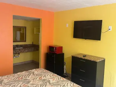 a bedroom with a bed and a flat screen tv at Apollo Inn - Downtown in Kissimmee