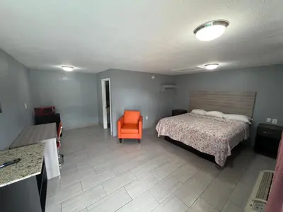 a bedroom with a bed and an orange chair at Apollo Inn - Downtown in Kissimmee
