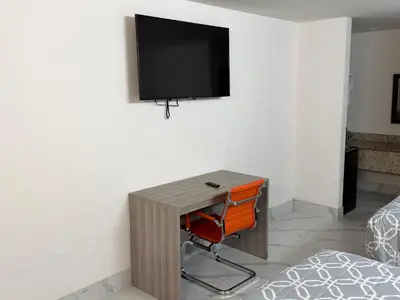 a room with a desk with a television on a wall at Apollo Inn - Downtown in Kissimmee