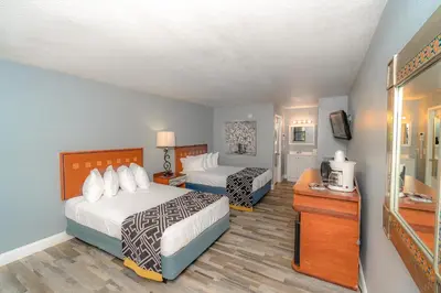 a hotel room with two beds and a television at Sunshine Inn in Kissimmee