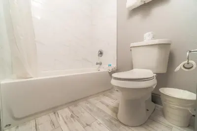 a white bathroom with a toilet and a bath tub at Sunshine Inn in Kissimmee