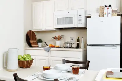 a kitchen with white cabinets and a table with food at InTown Suites Extended Stay Orlando FL - South in Orlando