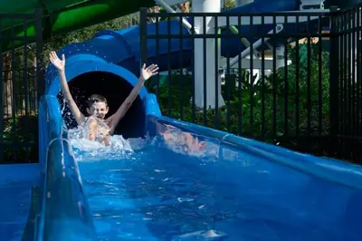 a young child is sliding down a water slide at Fantastic Condo - 2 Miles from Disney Pool View Windsor Hills in Orlando