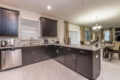 a kitchen with dark brown cabinets and a dining room at Enchanting Escape Private Pool SPA Games Room in Orlando