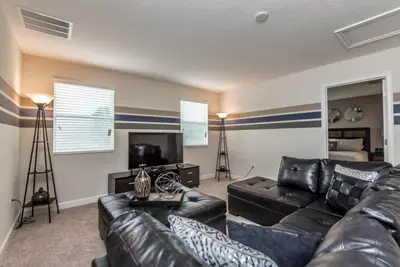 a living room with a leather couch and a television at Enchanting Escape Private Pool SPA Games Room in Orlando