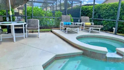 a patio with a table and chairs next to a pool at Affordable Luxury Home Near Walt Disney World - Sunshine Villa at Glenbrook Resort, Orlando, Florida in Orlando