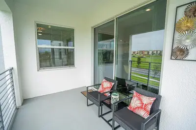 a balcony with two chairs and a glass table at Only 5 Miles from Disney! Free Water Park! 2 Bed, 2 Bath Condo, Sleeps 8 in Kissimmee