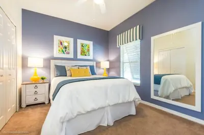 a blue bedroom with a large bed and a mirror at Bella Vidatown Home With Full Size Pool! Townhouse in Kissimmee