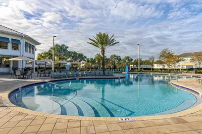a large swimming pool with chairs and umbrellas at Storey Lake - Private Pool Home 10 Min to Disney in Kissimmee
