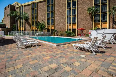a group of lounge chairs and a pool in front of a building at The Adventure Hotel by the Parks in Orlando