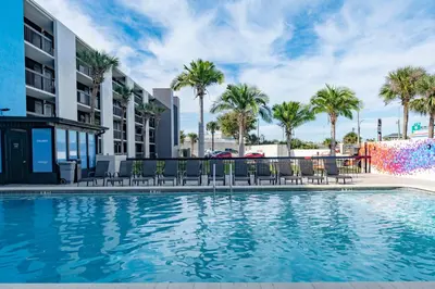 a pool with chairs and palm trees in front of a building at Hotel Monreale Express International Drive Orlando in Orlando