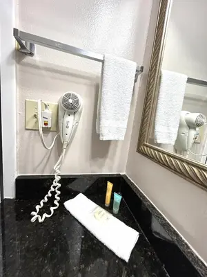 a bathroom with a hair dryer and a mirror at Shining Light Inn & Suites in Kissimmee