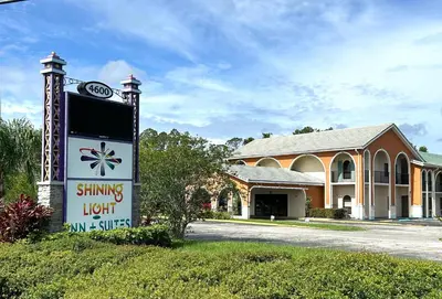 a sign in front of a building with a hotel at Shining Light Inn & Suites in Kissimmee