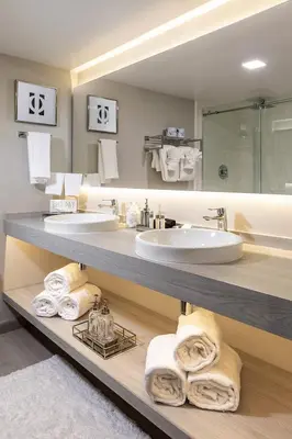 a bathroom with two sinks and towels on a shelf at Palazzo Lakeside Hotel in Kissimmee