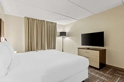 a hotel room with a bed and a flat screen tv at Sonesta Essential Orlando Airport in Orlando
