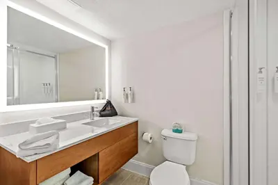 a bathroom with a sink and a toilet and a mirror at Sonesta Essential Orlando Airport in Orlando