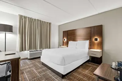 a hotel room with a large white bed and a desk at Sonesta Essential Orlando Airport in Orlando