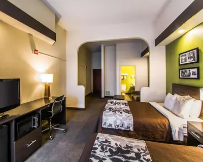 a hotel room with two beds and a desk at Sleep Inn & Suites Orlando International Airport in Orlando