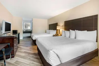 a hotel room with two beds and a desk and a television at Clarion Inn & Suites Kissimmee-Lake Buena Vista South in Kissimmee