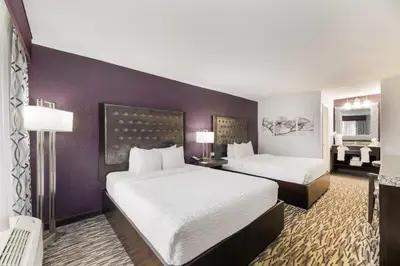 two beds in a hotel room with purple walls at Clarion Inn & Suites Across From Universal Orlando Resort in Orlando