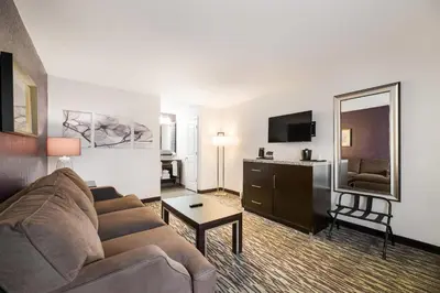 a living room with a couch and a mirror at Clarion Inn & Suites Across From Universal Orlando Resort in Orlando