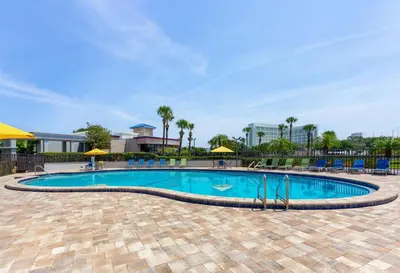 a pool at a resort with chairs and umbrellas at Days Inn by Wyndham Orlando Conv. Center/International Dr in Orlando