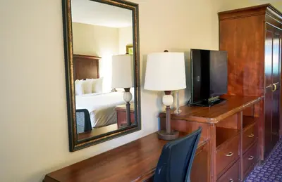 a hotel room with a mirror and a desk with a television at Rosen Inn International Near The Parks in Orlando