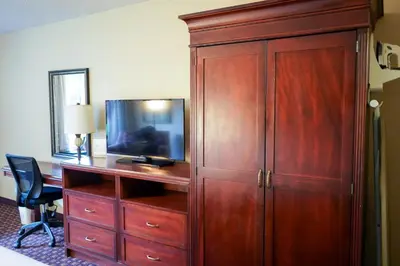 a large wooden cabinet with a tv and a desk at Rosen Inn Closest to Universal in Orlando