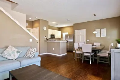 a living room and kitchen with a couch and a table at Amazing townhouse fits 10 in gated community 10 min to Disney! in Kissimmee