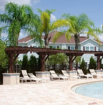a group of lounge chairs and a wooden pergola by a pool at 3 Bedroom townhouse fits 8, 10' to Disney parks! in Kissimmee