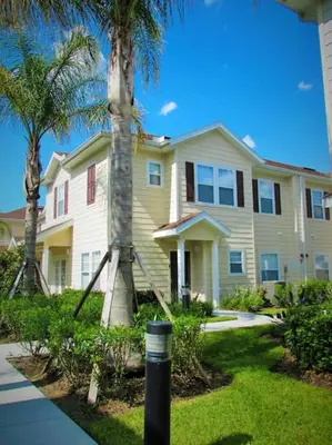 a house with a palm tree in front of it at 3 Bedroom townhouse in luxury Resort, sleeps 8, 10 min to Disney! in Kissimmee
