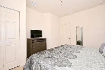 a bedroom with a bed and a flat screen tv at Luxury 3 bedroom townhouse, comfortable sleeps 8 Super close to Disney! in Kissimmee