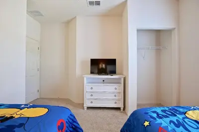 a bedroom with a bed and a tv on a dresser at Luxury 3 bedroom townhouse, comfortable sleeps 8 Super close to Disney! in Kissimmee