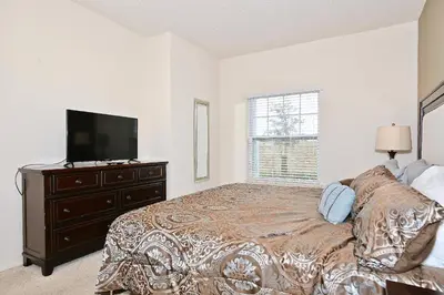 a bedroom with a bed and a tv on a dresser at Fantastic Townhouse in Lux community sleeps 8, 10' to Disney!! in Kissimmee